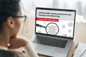 Woman reading an infographic about GMP-grade cell culture products on a laptop computer
