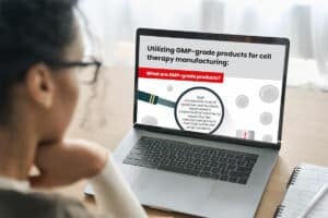 Woman reading an infographic about GMP-grade cell culture products on a laptop computer